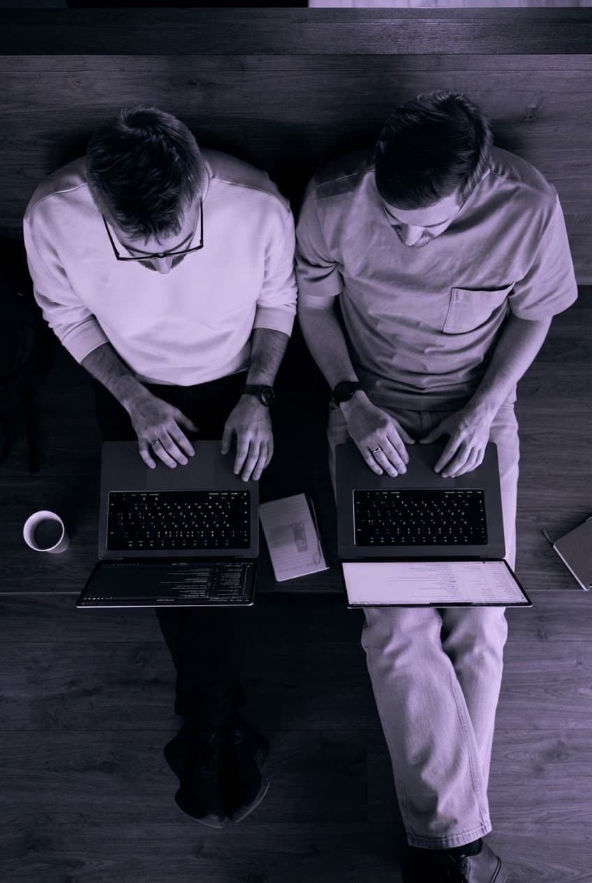 The two founders of CIRO Effort working side by side on their laptops, photographed from above